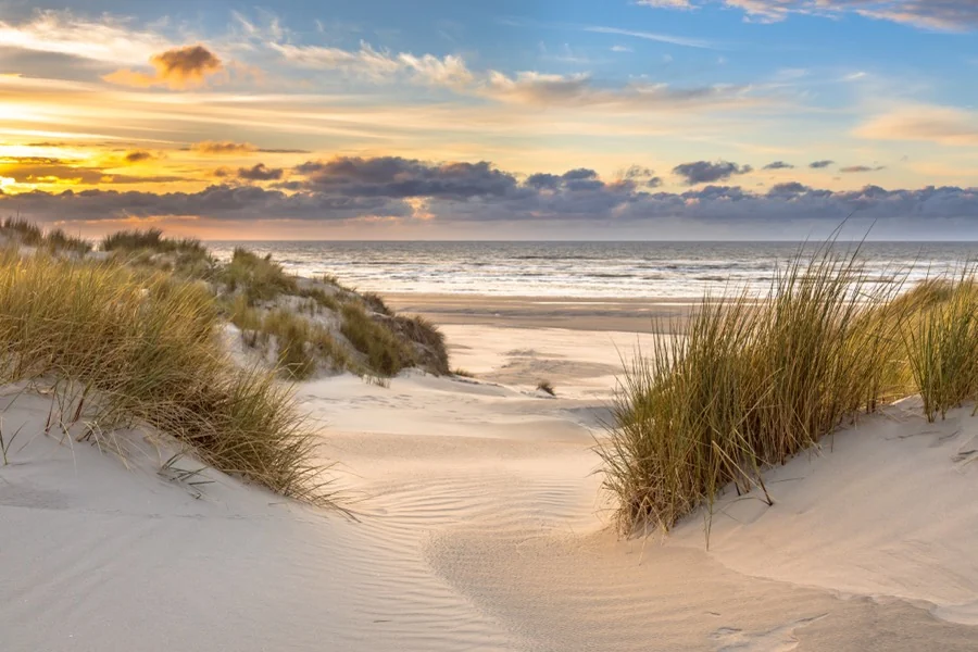 Duinovergang naar het strand bij zonsondergang